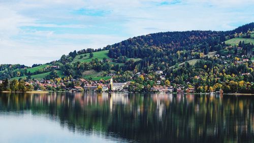 Scenic view of lake by townscape against sky