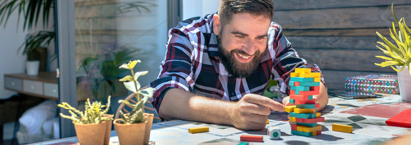 Bearded man catching jenga game piece in rooftop party