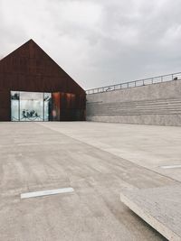 Empty road by building against sky