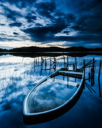 Scenic view of lake and boat against sky during sunrise