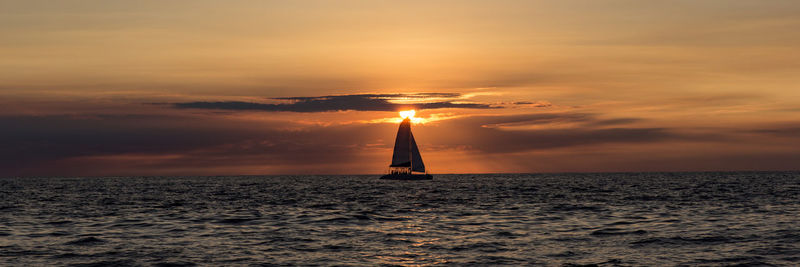 Silhouette sailboat on sea against sky during sunset