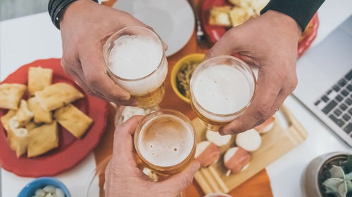 Toast with friend enjoying dinner together.  table with foods and glasses of beer in hands cheer up