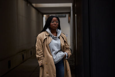 Young woman looking away while standing against wall