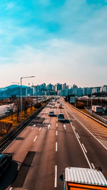 Vehicles on road against sky in city