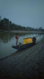 Man rowing boat in lake against sky