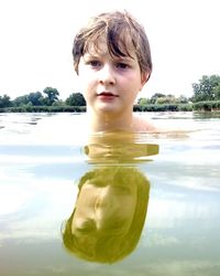 Portrait of shirtless boy swimming in lake against sky