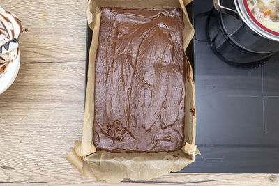 Baking tray filled entirely with thick cocoa mass, ready for baking, lying on the kitchen counter.