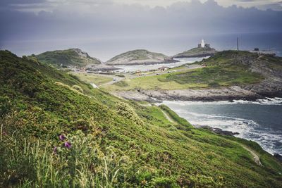 Scenic view of landscape by sea against sky