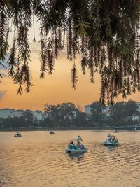 People on sea against sky during sunset