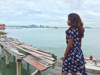 Woman standing on pier over sea against sky