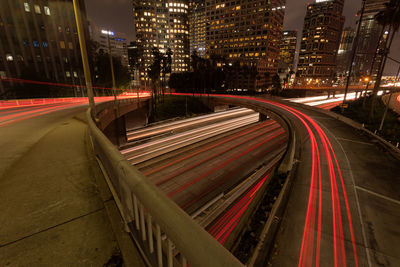 Light trails on bridge by illuminated buildings at night