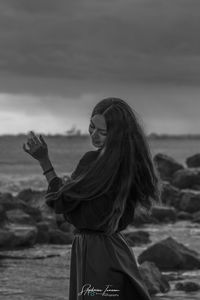 Woman standing at beach against sky