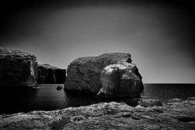 Rock formations by sea against sky