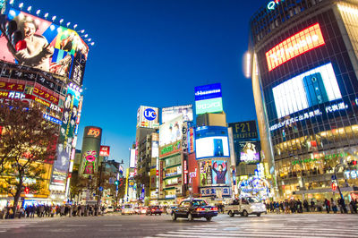 Crowd on illuminated city against clear sky at night