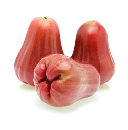 Close-up of hand holding strawberry over white background