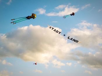 Low angle view of kites with text flying in sky