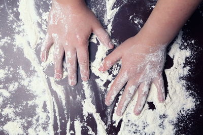 Cropped image of kid hands covered in flour on kitchen counter