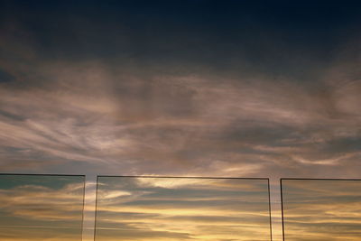 Low angle view of electricity pylon against dramatic sky