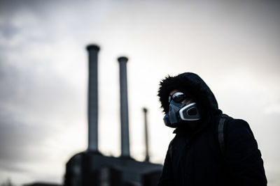 Portrait of young man photographing against sky with mask on after corona virus