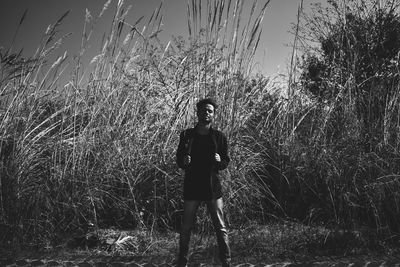 Portrait of young man standing on land against plants