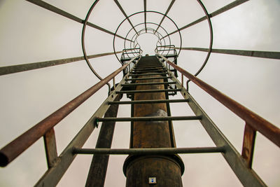 Low angle view of metallic ladder against sky