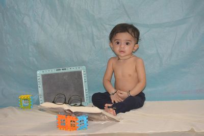 Portrait of shirtless boy sitting at toy at home