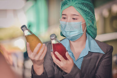 Close-up of woman wearing mask inspecting drinks in factory