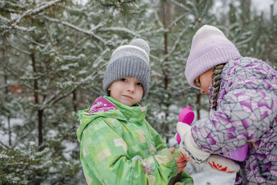 Portrait of girl playing with brother during winter