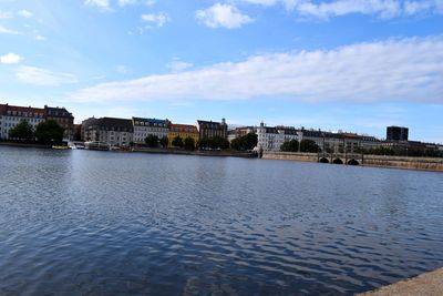 River by buildings in city against sky