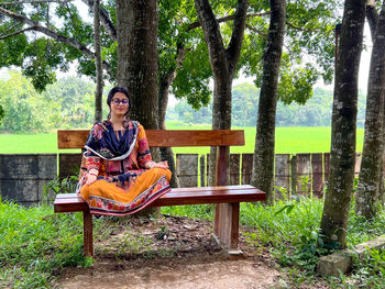 Young woman using laptop while sitting on bench in park