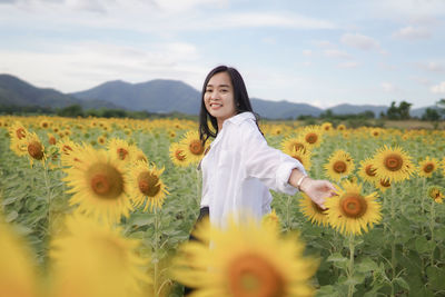 Portrait of young woman standing amidst flowers
