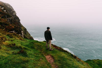 Rear view of man looking at sea while standing on mountain