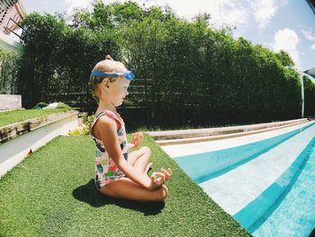 Girl doing yoga by swimming pool