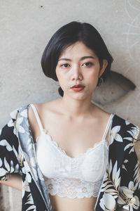 Portrait of young woman standing against wall