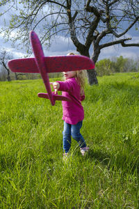 Rear view of girl standing on grassy field