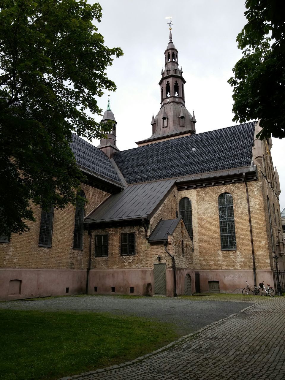 architecture, building exterior, built structure, religion, church, place of worship, spirituality, tree, cross, low angle view, sky, cathedral, clear sky, tower, sunlight, day, facade, history