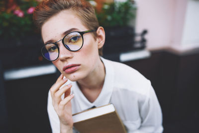 Portrait of young woman holding eyeglasses