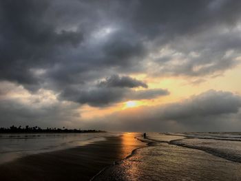 Scenic view of sea against dramatic sky during sunset