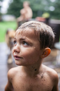 Close-up of wet messy boy looking away at backyard