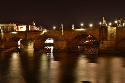 Illuminated bridge over river against sky at night