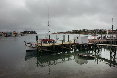 Boats moored at harbor against sky