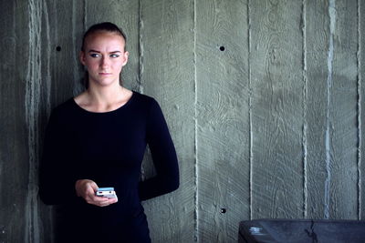 Woman standing against wooden wall