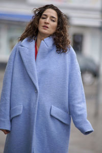 Portrait of woman in coat standing on road during winter