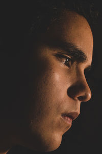 Close-up portrait of young man against black background