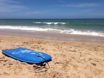 Body board on beach against sky