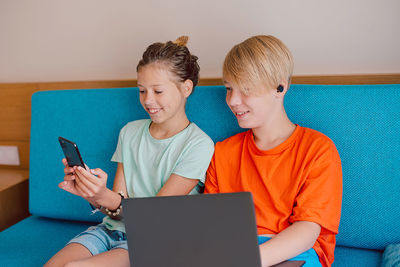 Young woman using digital tablet while sitting on sofa at home