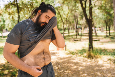 Man wiping sweat by stretching t-shirt