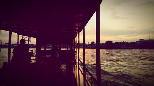 Silhouette bridge over river against sky during sunset