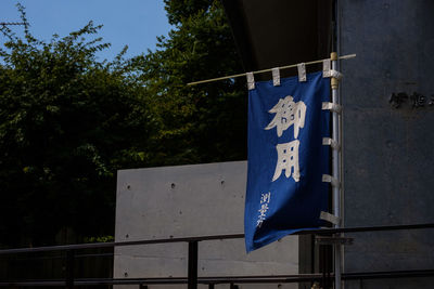 Low angle view of flags hanging on pole against trees