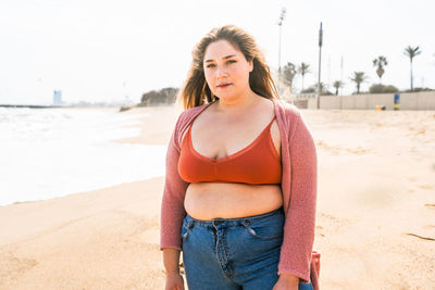 Portrait of young woman standing at beach